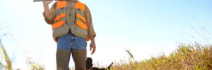 Man, dog and bush for hunting hobby, shotgun practice and stalking prey together in nature. Mature person, pet animal and hunter support in field to guide on mockup, thinking and outdoor tracking.